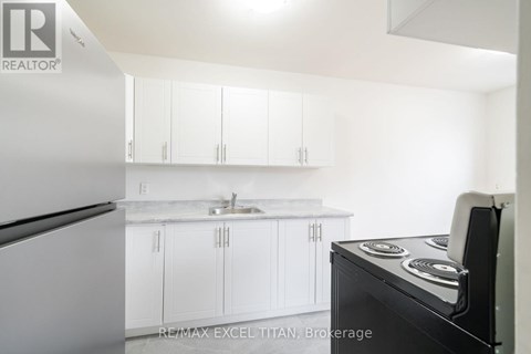 A white kitchen with a black stove top oven.