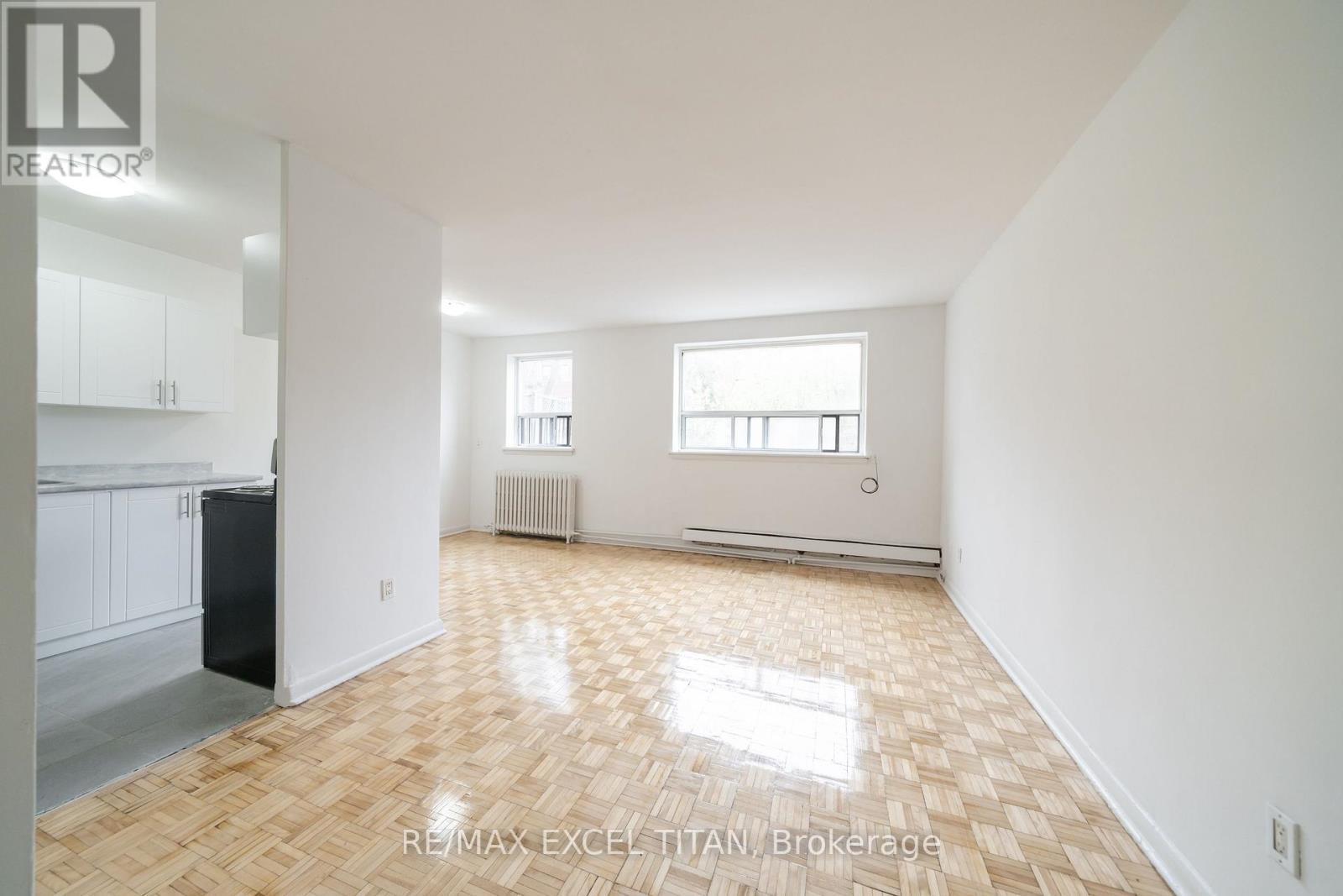 A spacious, empty room with a wooden floor and white walls.