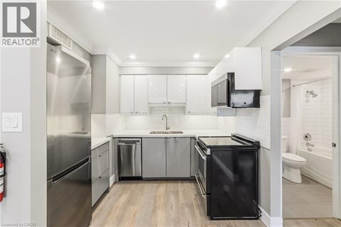 A modern kitchen with white cabinets and black appliances.