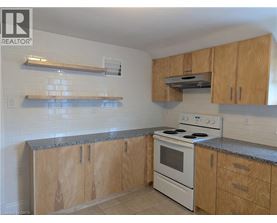 A kitchen with a stove top oven and wooden cabinets.