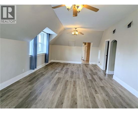 A spacious room with wood flooring and a ceiling fan.