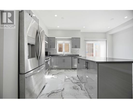 A modern kitchen with stainless steel appliances and a marble countertop.