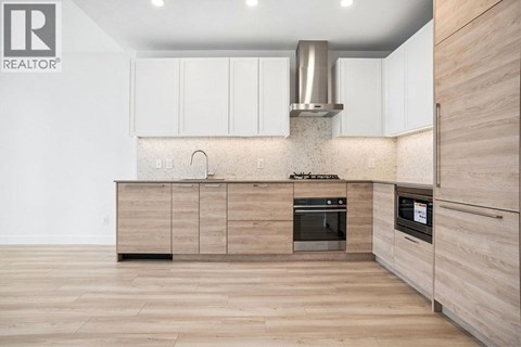 A modern kitchen with wooden cabinets and a stainless steel range hood.