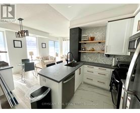A modern kitchen with a black countertop and stainless steel appliances.