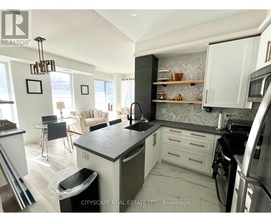 A modern kitchen with a black countertop and stainless steel appliances.