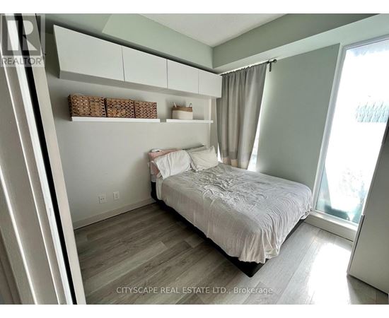 A bedroom with a bed, nightstand, and window.