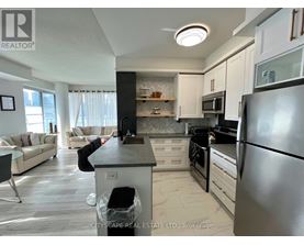 A modern kitchen with a black refrigerator and white cabinets.