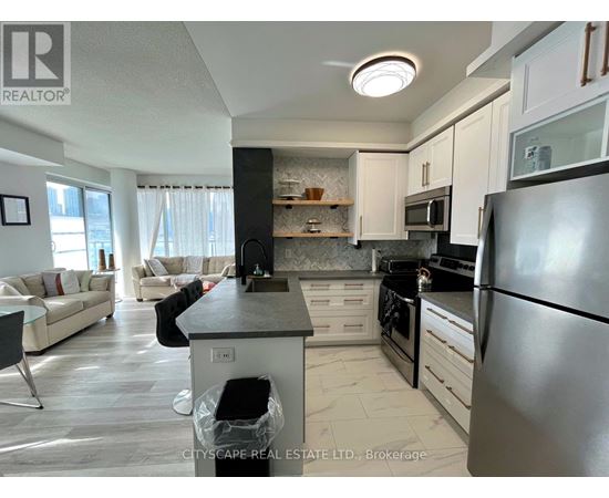 A modern kitchen with a black refrigerator and white cabinets.