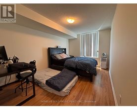 A bedroom with a bed, a desk, and a chair.