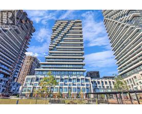 A tall, modern building with a glass facade stands in the foreground of a cityscape.