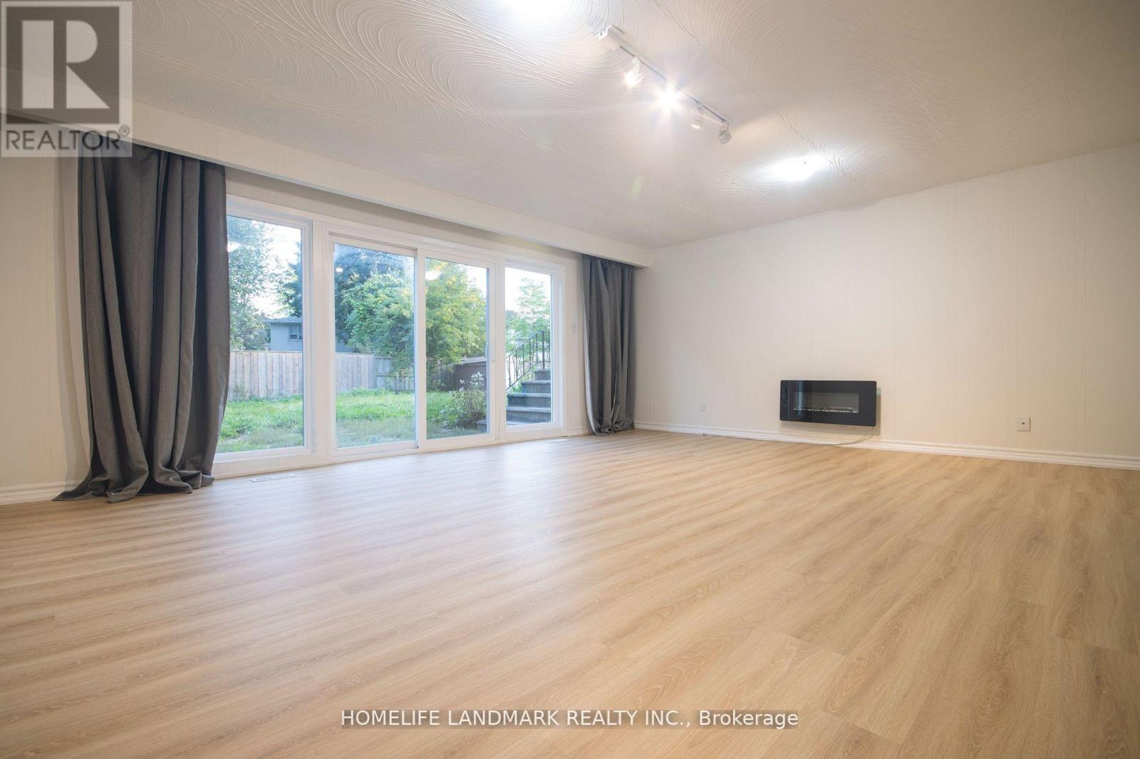 A spacious room with wooden flooring and a television in the corner.
