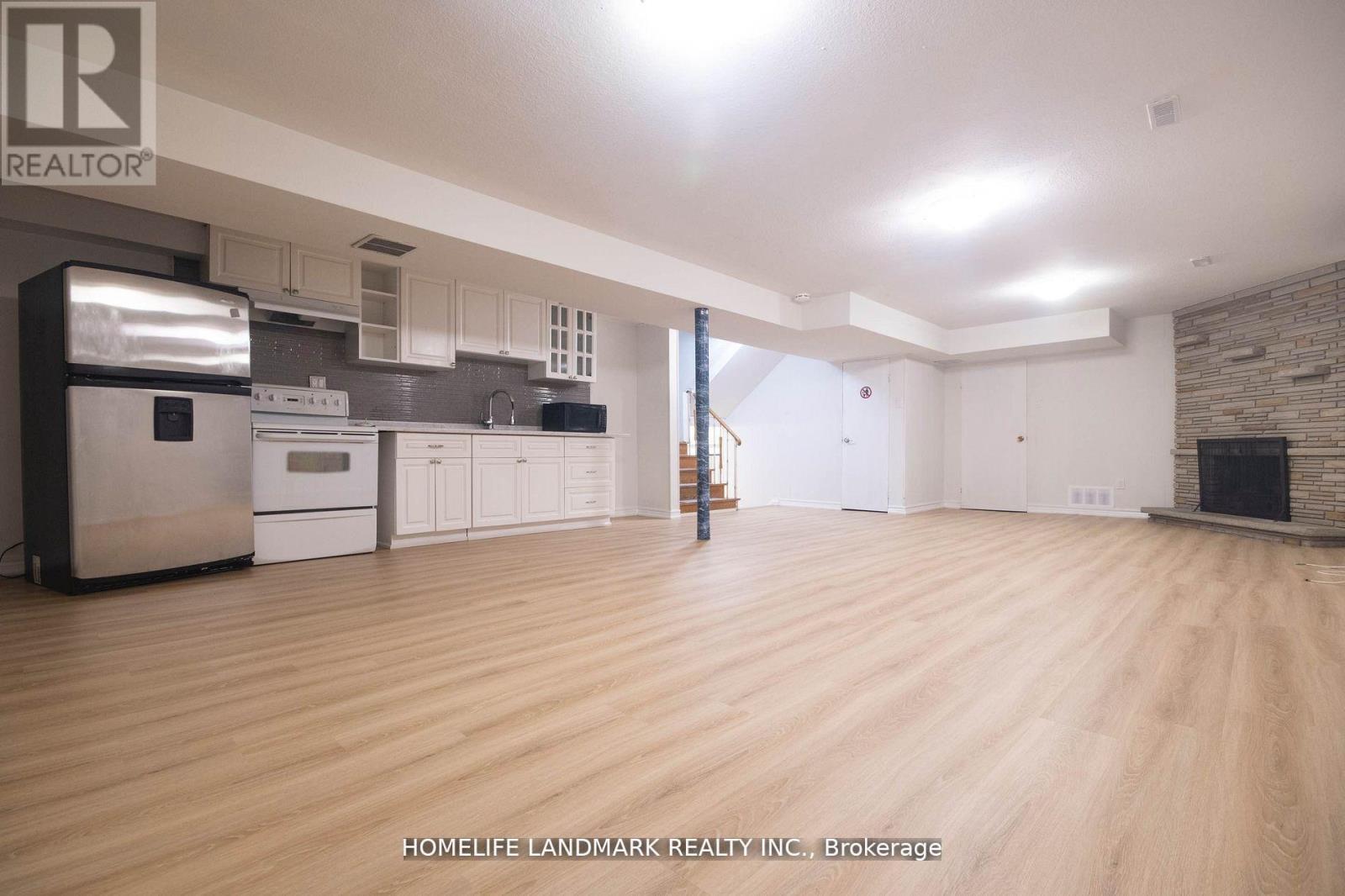 A spacious kitchen with wooden floors and a brick accent wall.