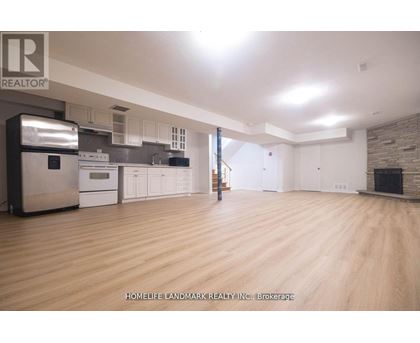 A spacious kitchen with wooden floors and a brick accent wall.