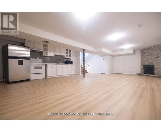 A spacious kitchen with wooden floors and a brick accent wall.