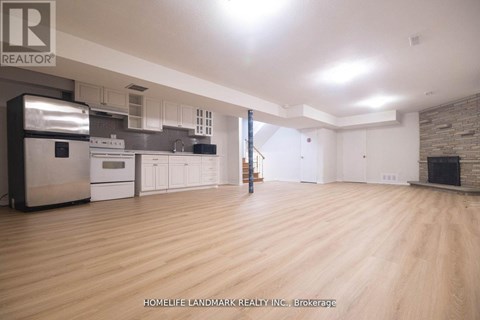 A spacious kitchen with wooden floors and a brick accent wall.