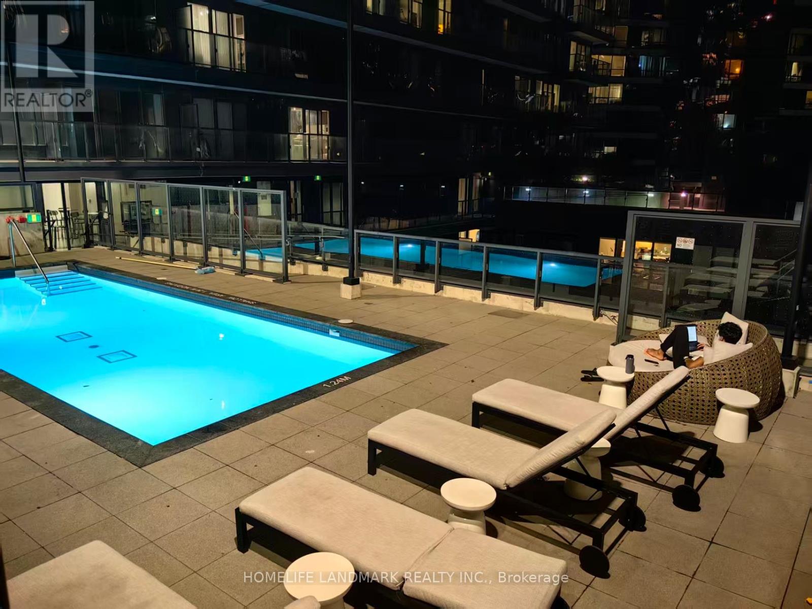 A pool area with loungers and a building in the background.