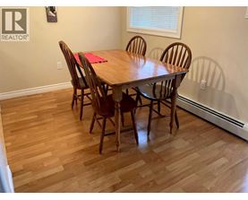 A dining room with a wooden table and chairs.