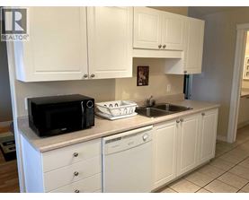 A kitchen with white cabinets and a black microwave.