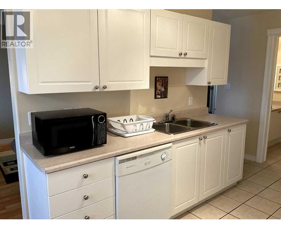 A kitchen with white cabinets and a black microwave.