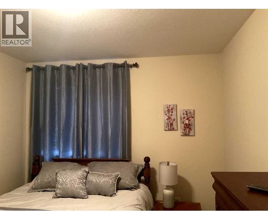 A bedroom with a bed, nightstand, and lamp.