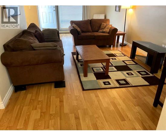 A living room with a brown couch and a rug.