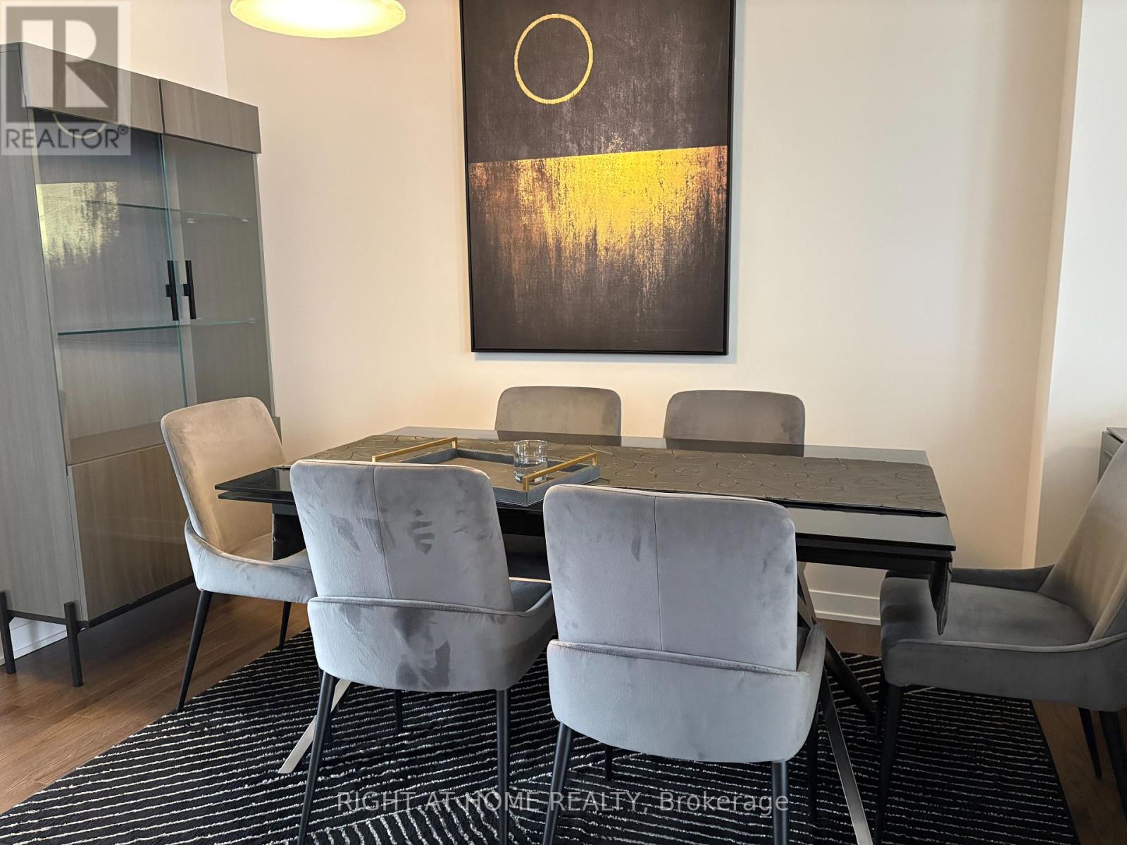 A modern dining room with a black and white rug and a large painting on the wall.