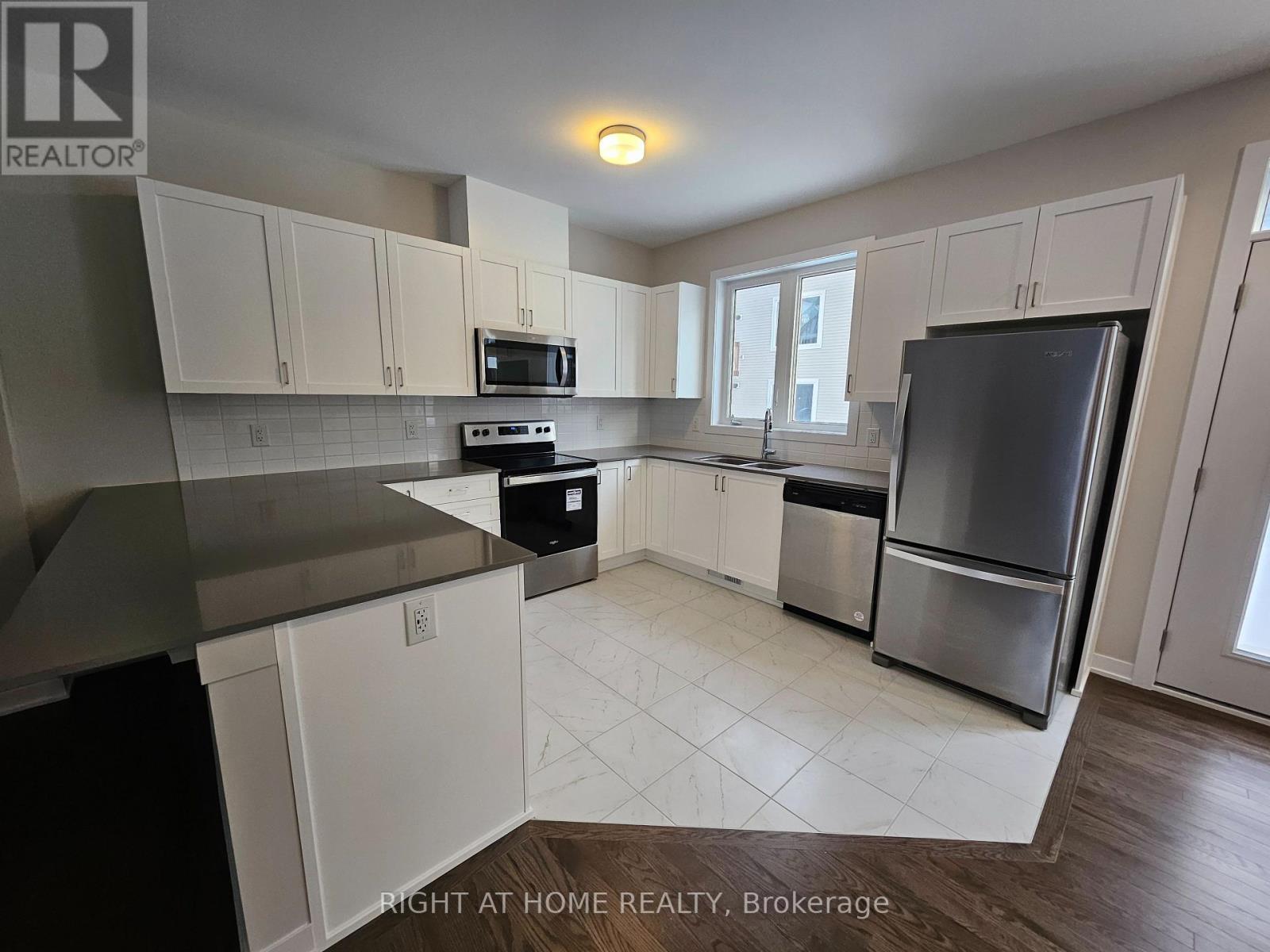 A kitchen with white cabinets and a black fridge.