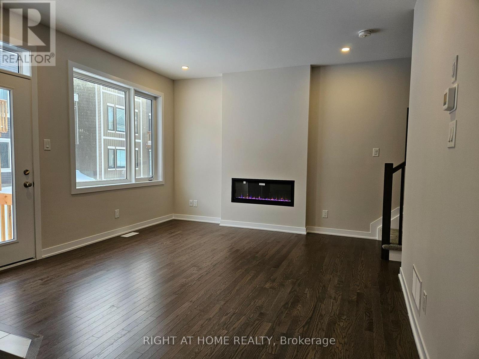 A spacious room with a fireplace and wooden flooring.