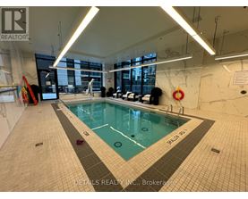 A swimming pool inside a building with a sign that says "DETAILS REALTY INC., Brokerage".