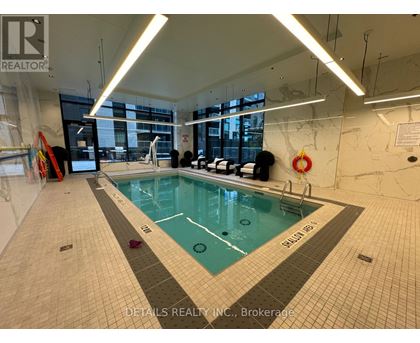 A swimming pool inside a building with a sign that says "DETAILS REALTY INC., Brokerage".