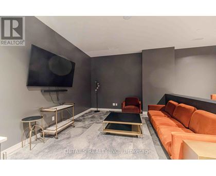 A living room with a grey floor and a black television mounted on the wall.