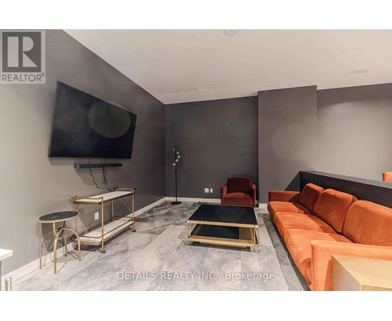 A living room with a grey floor and a black television mounted on the wall.