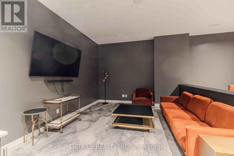 A living room with a grey floor and a black television mounted on the wall.
