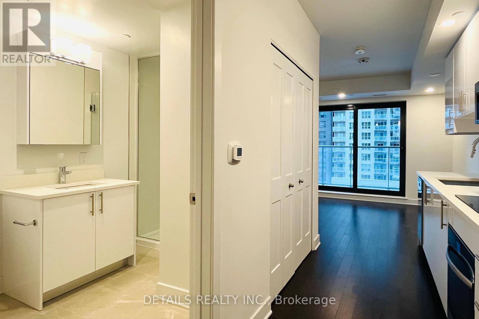 A modern kitchen with white cabinets and a large window.