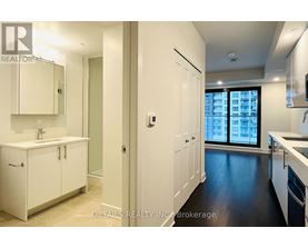 A modern kitchen with white cabinets and a large window.