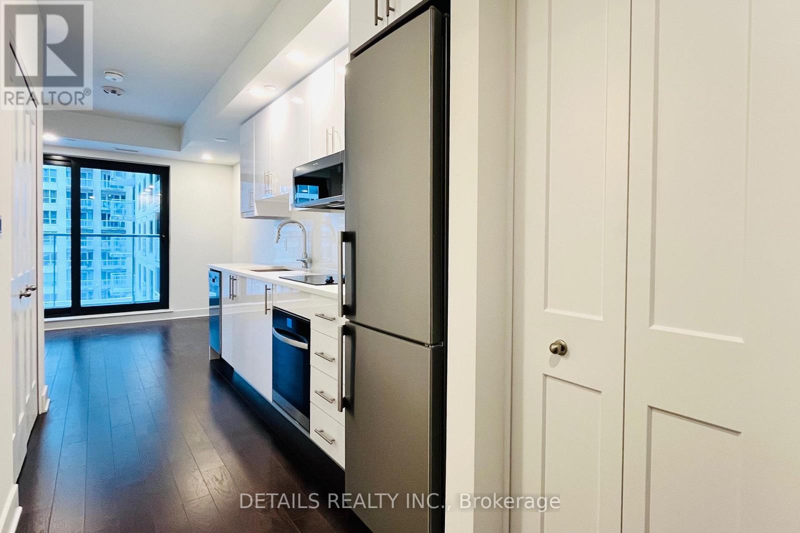 A modern kitchen with white cabinets and a stainless steel refrigerator.