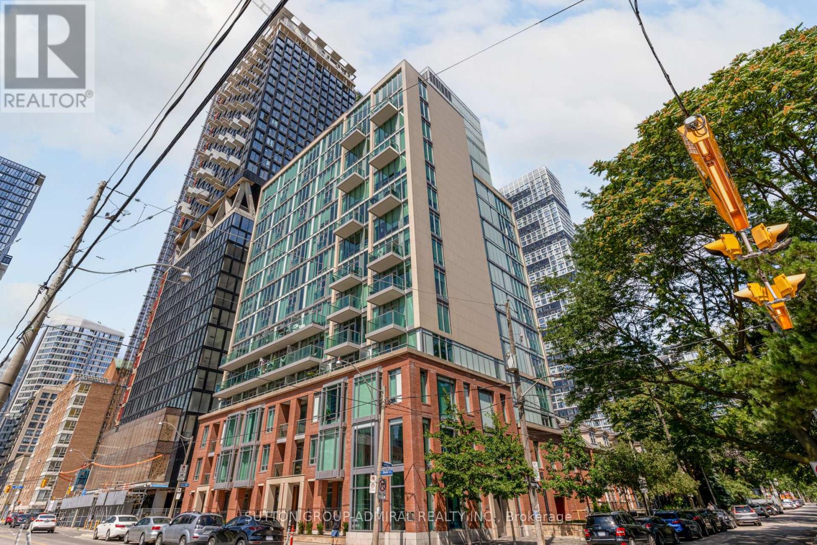 A tall building with a glass facade stands next to a shorter building with a brick facade.
