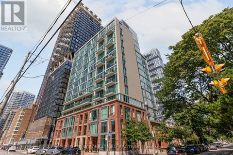 A tall building with a glass facade stands next to a shorter building with a brick facade.