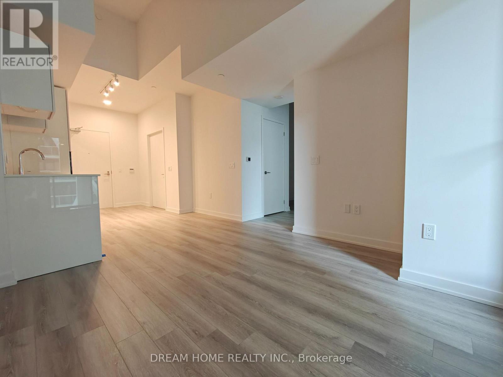 A room with wooden flooring and white walls, with a door on the right side.