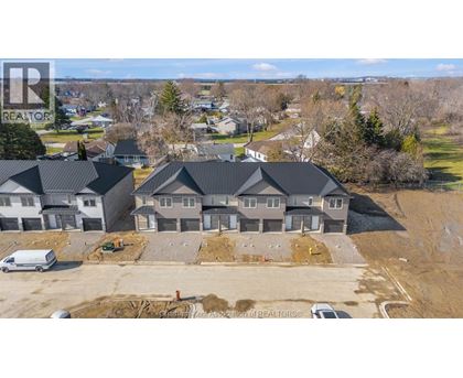 A real estate company's logo is watermarked on an aerial photo of a residential area with houses and construction.