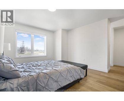 A bedroom with a large bed and a window overlooking a field.