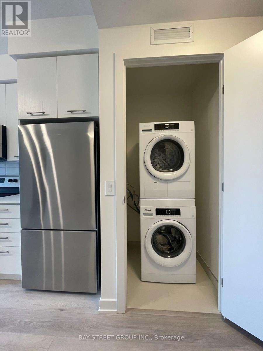 A modern kitchen with a stainless steel refrigerator and white washing machine.