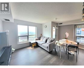 A living room with a grey couch, a white table, and a television.