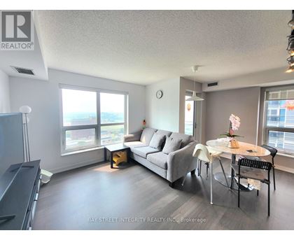 A living room with a grey couch, a white table, and a television.