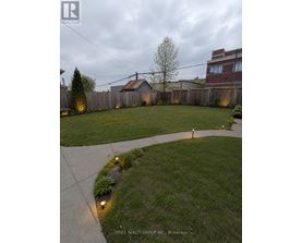 A backyard with a concrete walkway and grassy area.