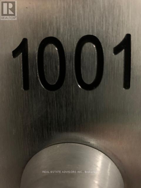 A metal plate with the number 1001 and the logo of a realtor.