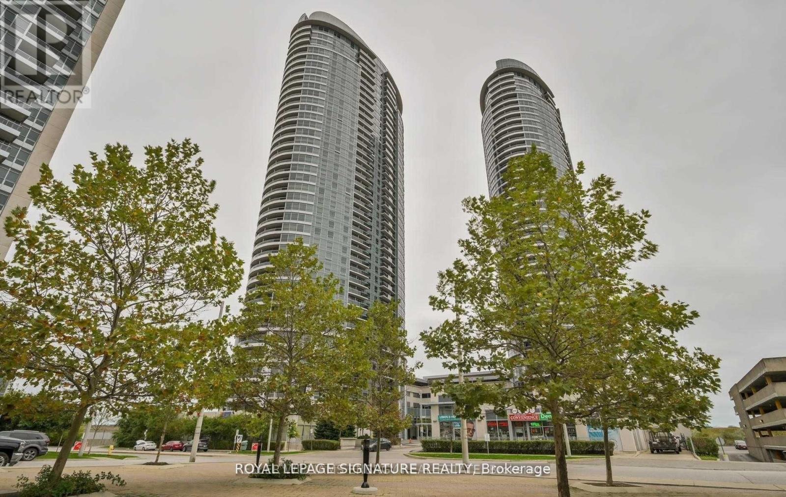 Two tall buildings are surrounded by trees and have a sign that says "Royal LePage Signature Realty Brokerage.".