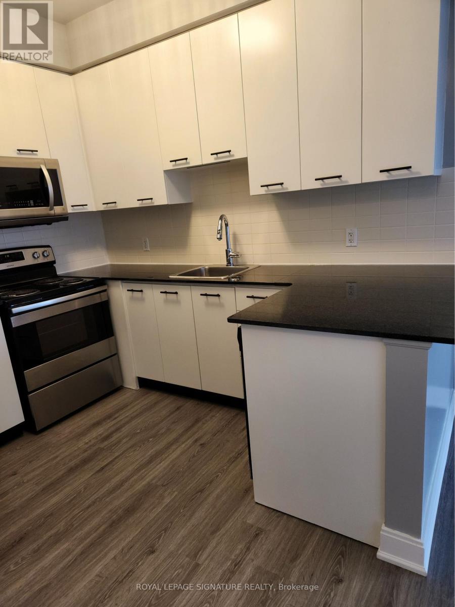 A kitchen with white cabinets and a black countertop.