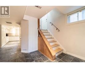 A staircase with a wooden handrail and white walls.
