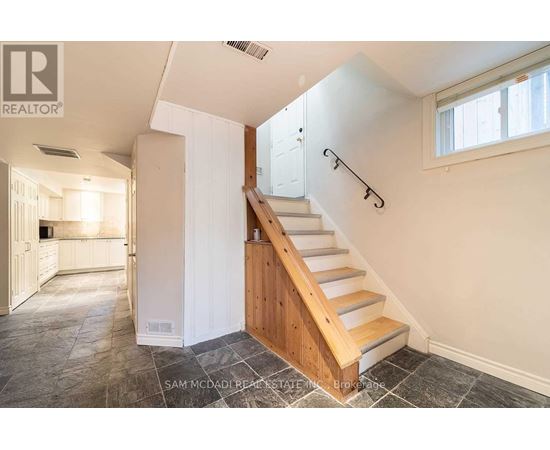 A staircase with a wooden handrail and white walls.